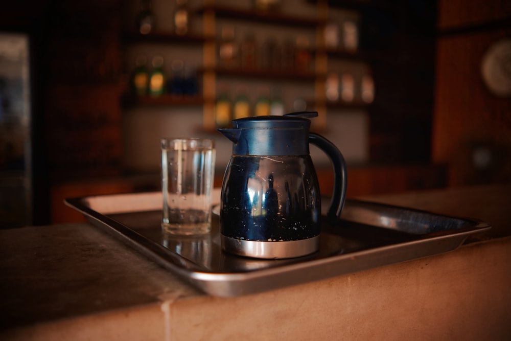 a glass of water and a tea pot on a tray