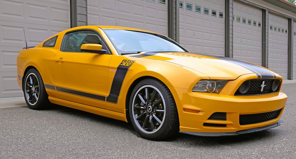 a yellow mustang parked in front of a garage