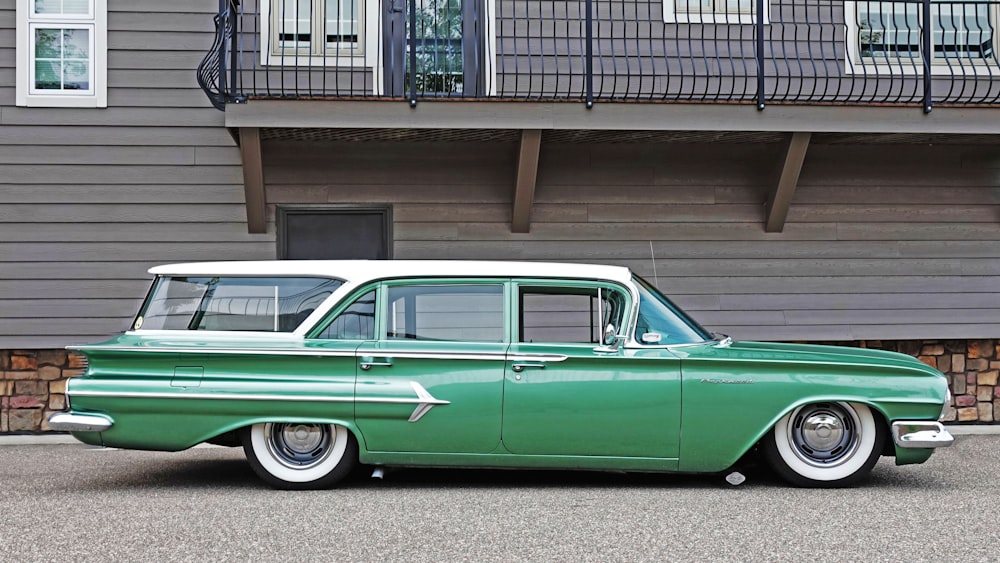 a green and white car parked in front of a building