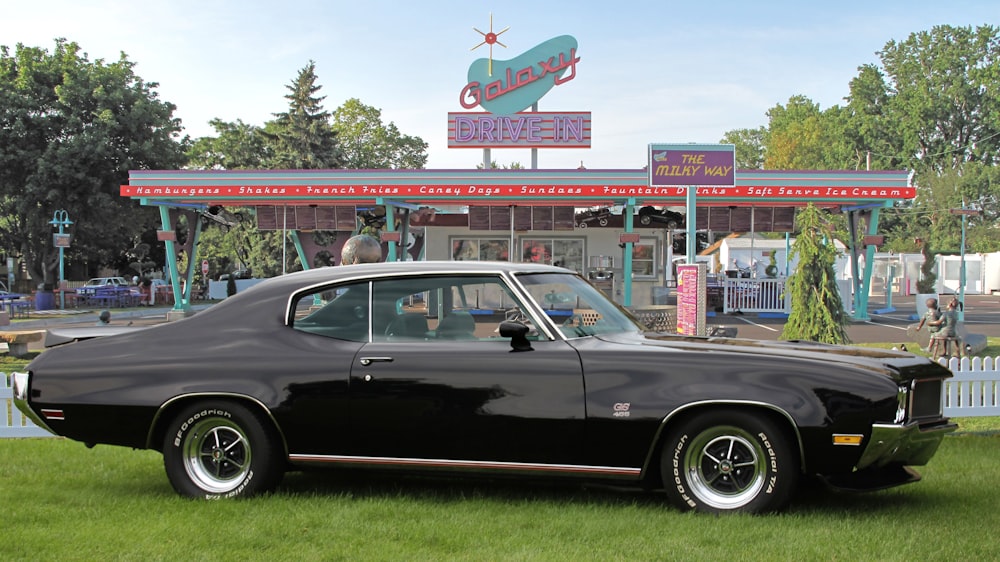 a black car parked in front of a gas station