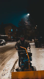 A team member spreading salt on an icy driveway as dusk settles.