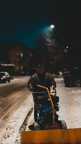 A team member spreading salt on an icy driveway as dusk settles.