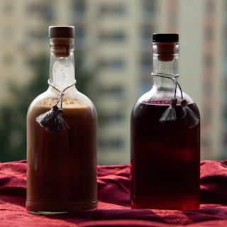 Close-up of amber-colored herbal bitters in glass bottles with urban cityscape blurred in the background