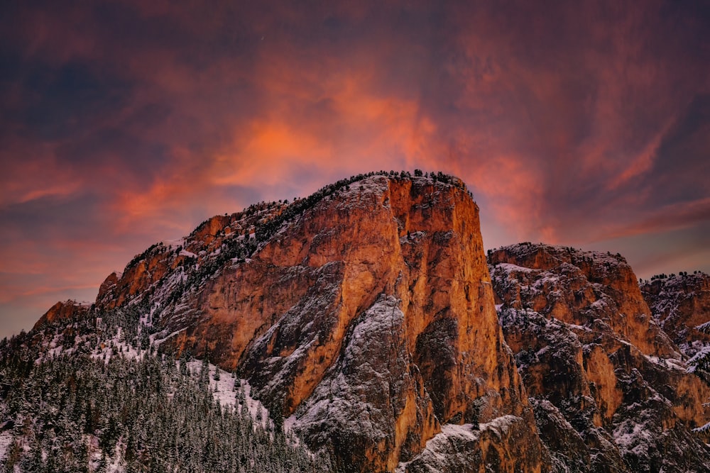 a mountain covered in snow under a cloudy sky