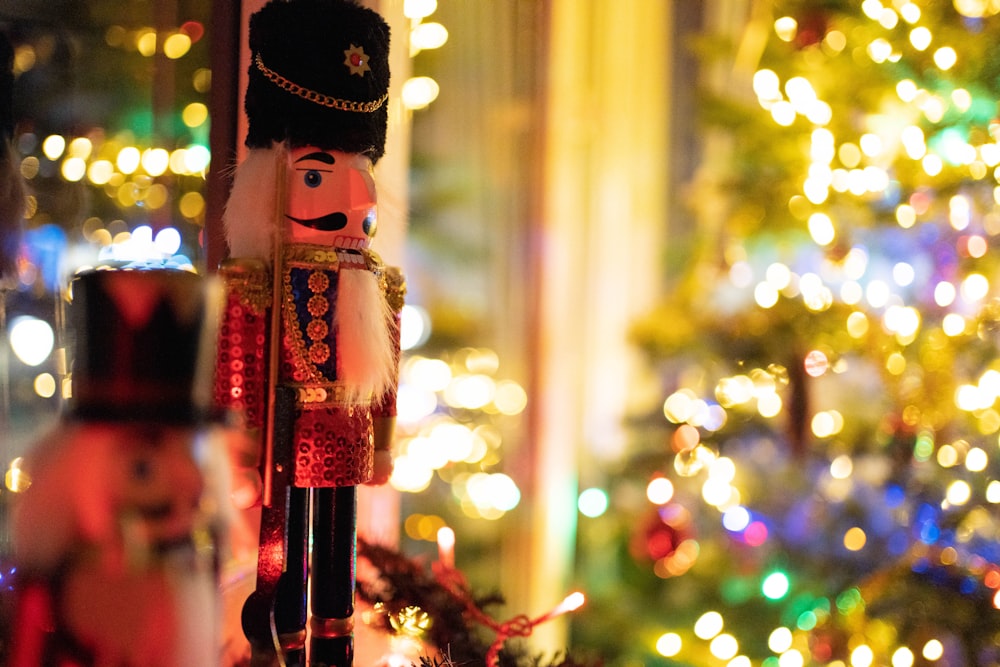 a nutcracker is standing in front of a christmas tree