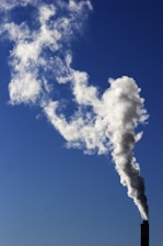 A clean, well-maintained chimney with smoke gently rising against a blue sky.