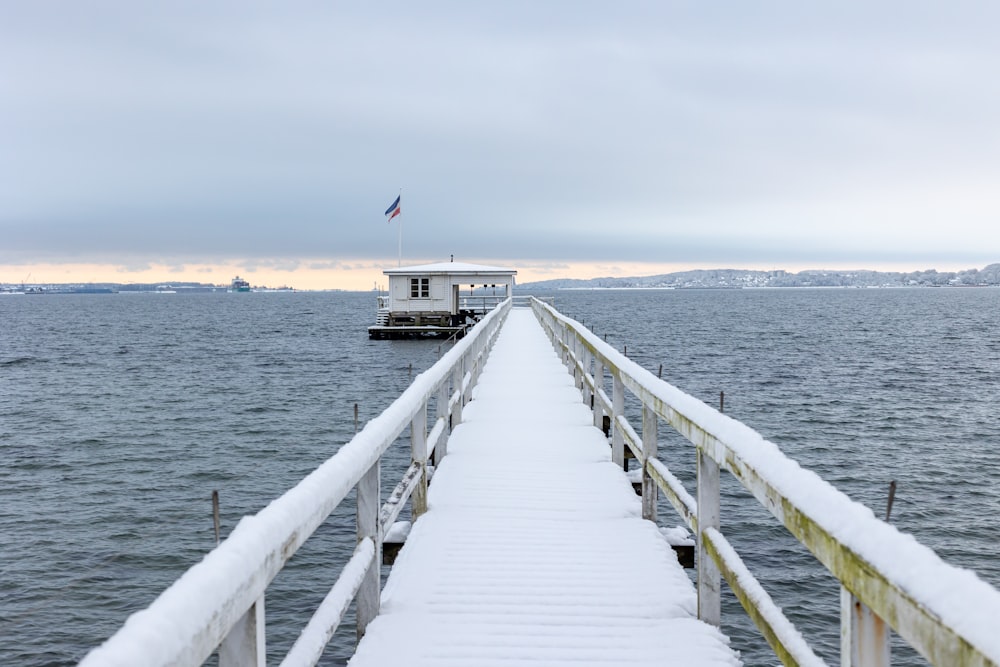 a pier with a boat in the water covered in snow