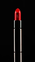 Close-up of a vibrant red lipstick tube on a white background