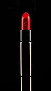 Close-up of a vibrant red lipstick tube on a white background