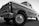 A classic vintage truck with a shiny surface and detailed front grille, viewed from a low angle emphasizing its robust build. The truck appears well-maintained with visible reflections on its body, highlighting the contours and craftsmanship of its era.