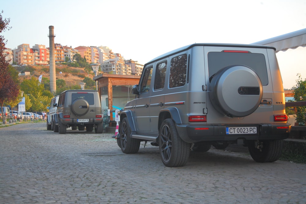 a couple of vehicles parked on a cobblestone road