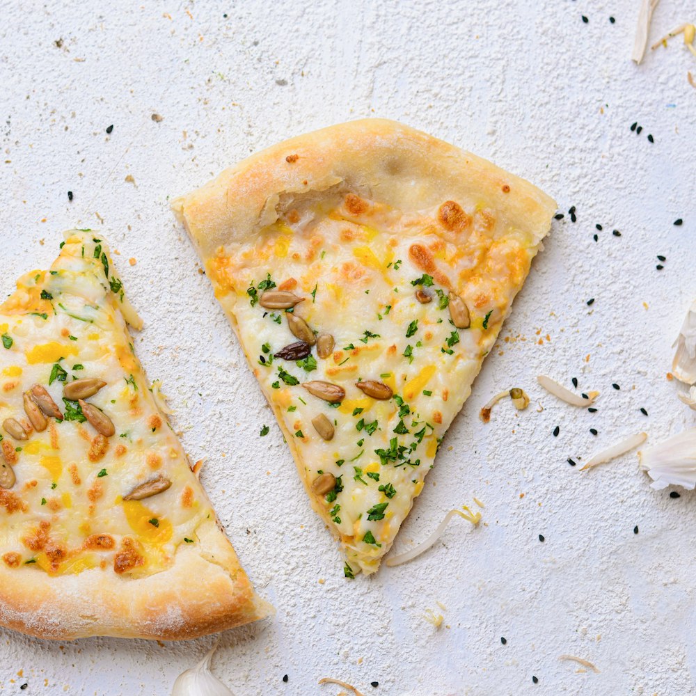 Deux tranches de pizza posées sur une surface blanche