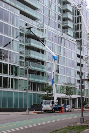 a crane is attached to a street light in front of a large building