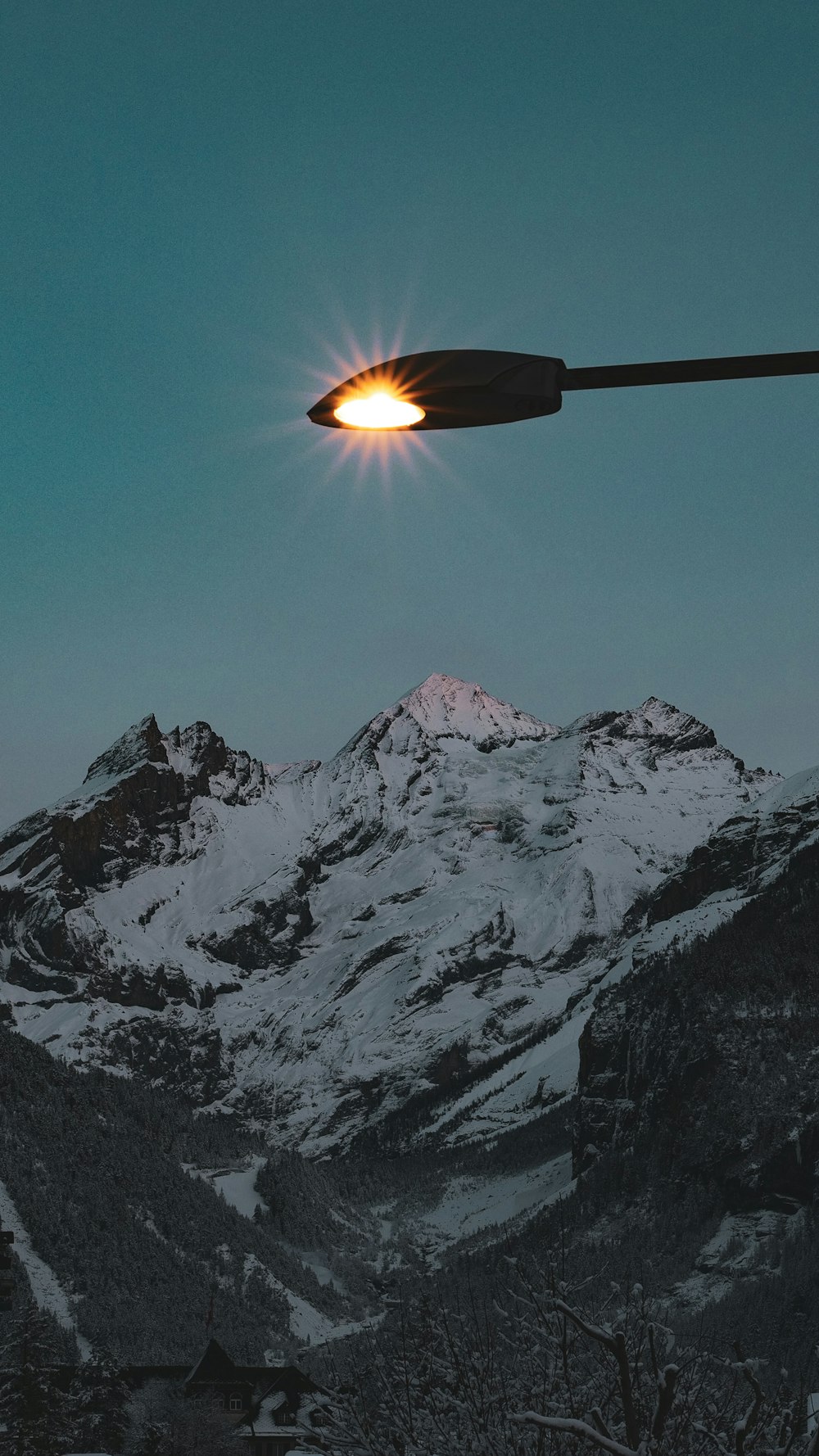 a street light in front of a snowy mountain