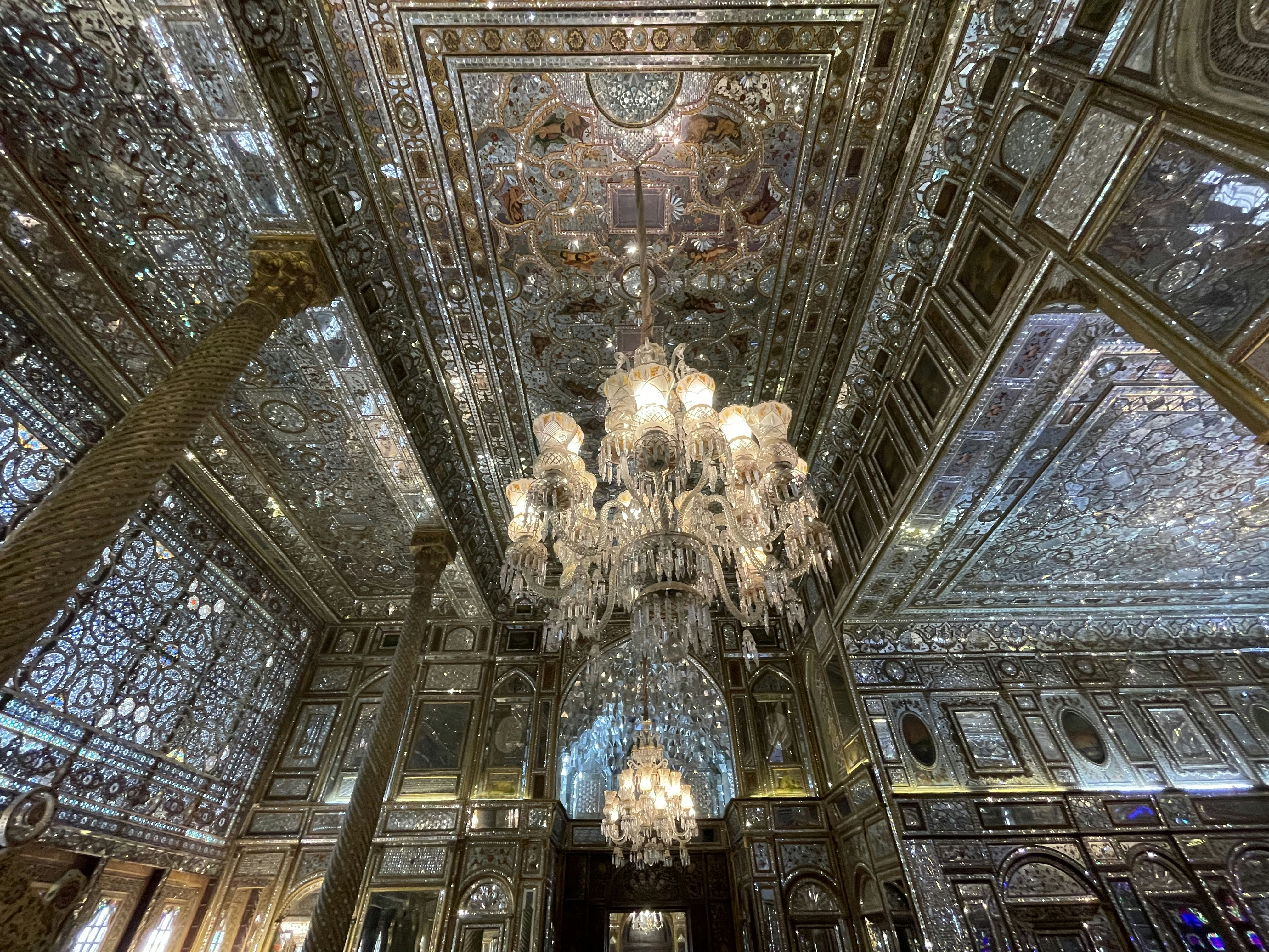 Ornate palace interior with mirror mosaic ceiling, carved marble jali screens, soft candlelight creating infinite reflections