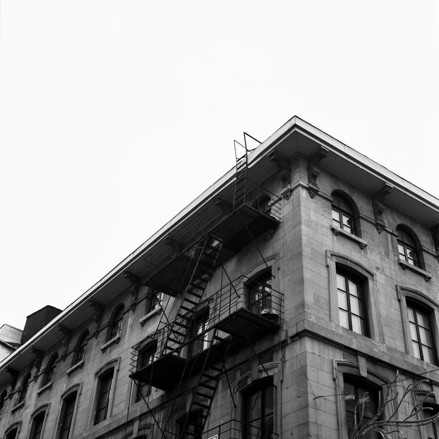 A black and white view of a Montreal stone apartment building with the iconic spiral exterior fire-escape staircases