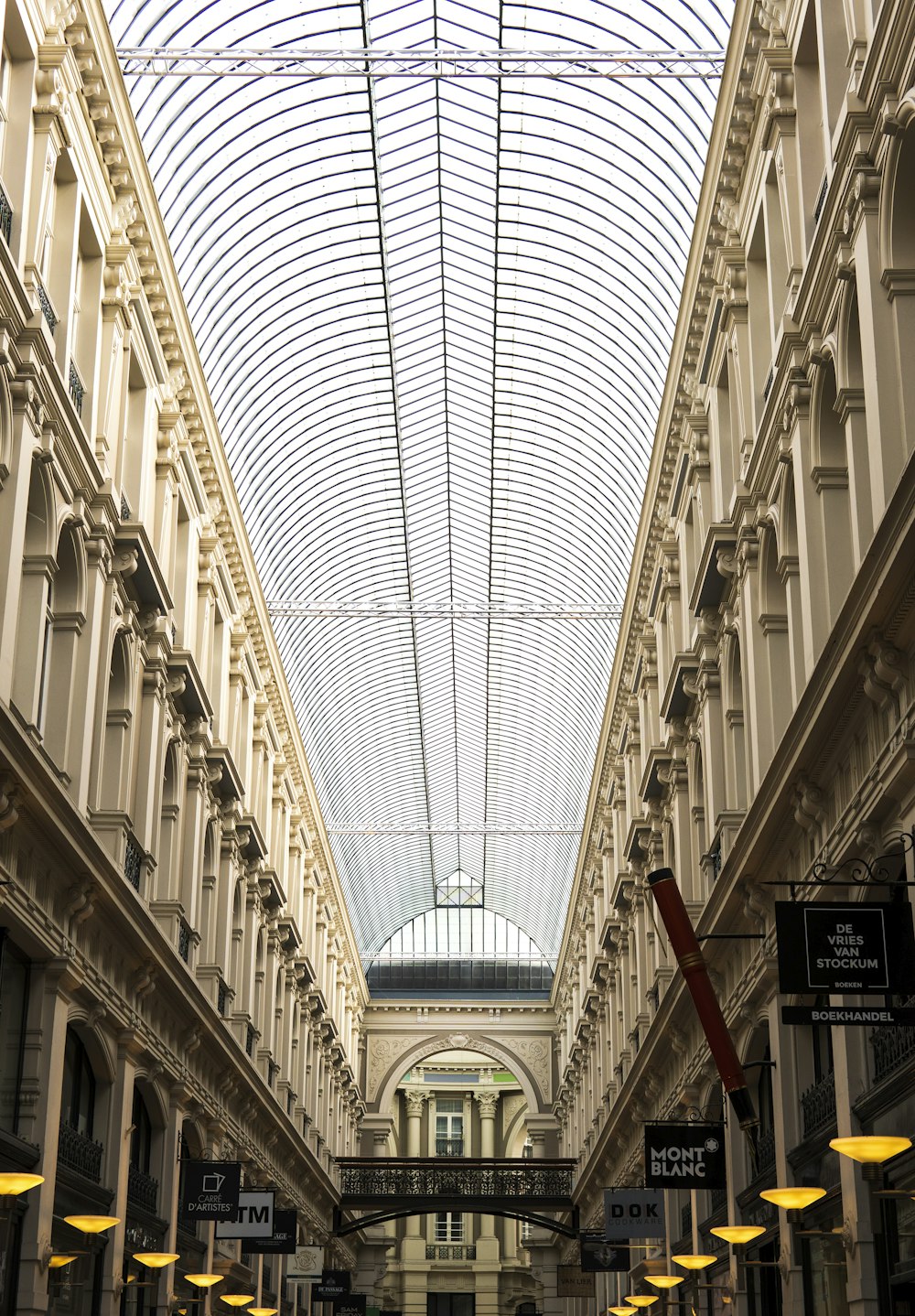 a large building with a glass ceiling and a few people walking down it