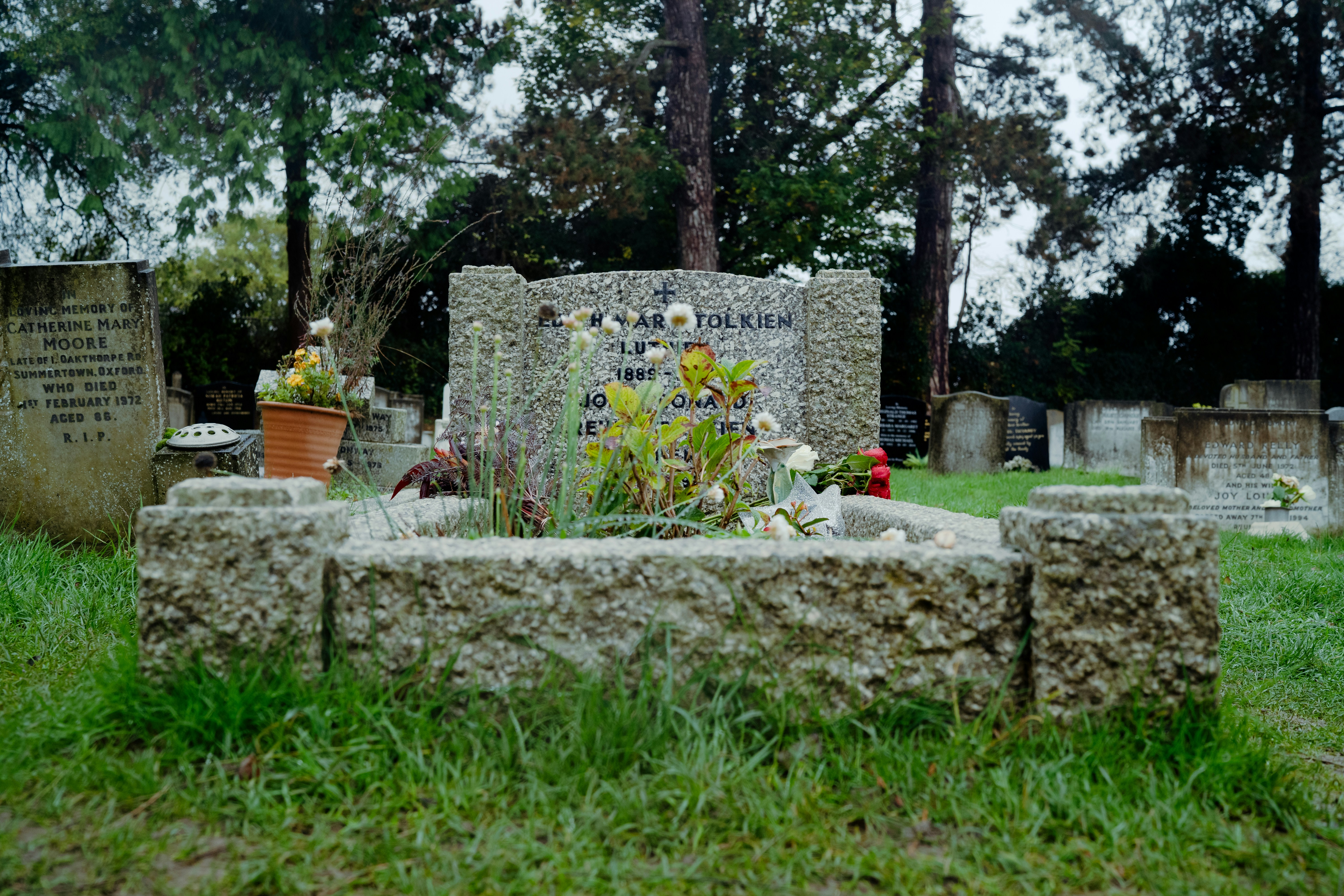 a grave with flowers and a potted plant in it