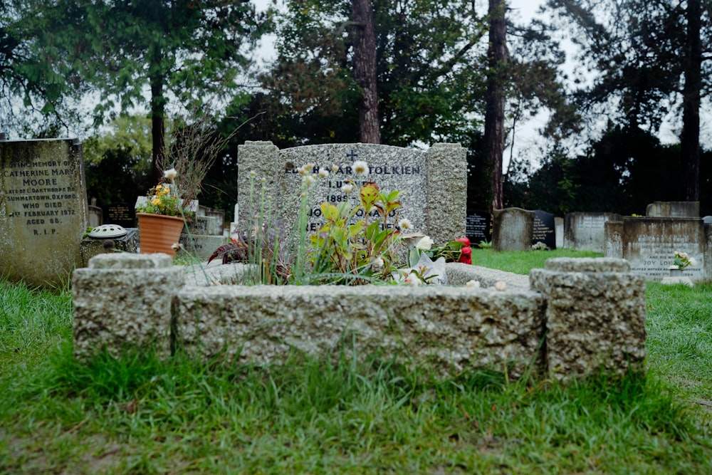 a grave with flowers and a potted plant in it
