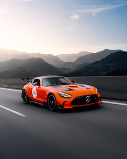 Front view of a bold Hyundai sports car on an open highway with mountains in the background.