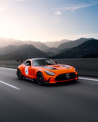 Front view of a bold Hyundai sports car on an open highway with mountains in the background.