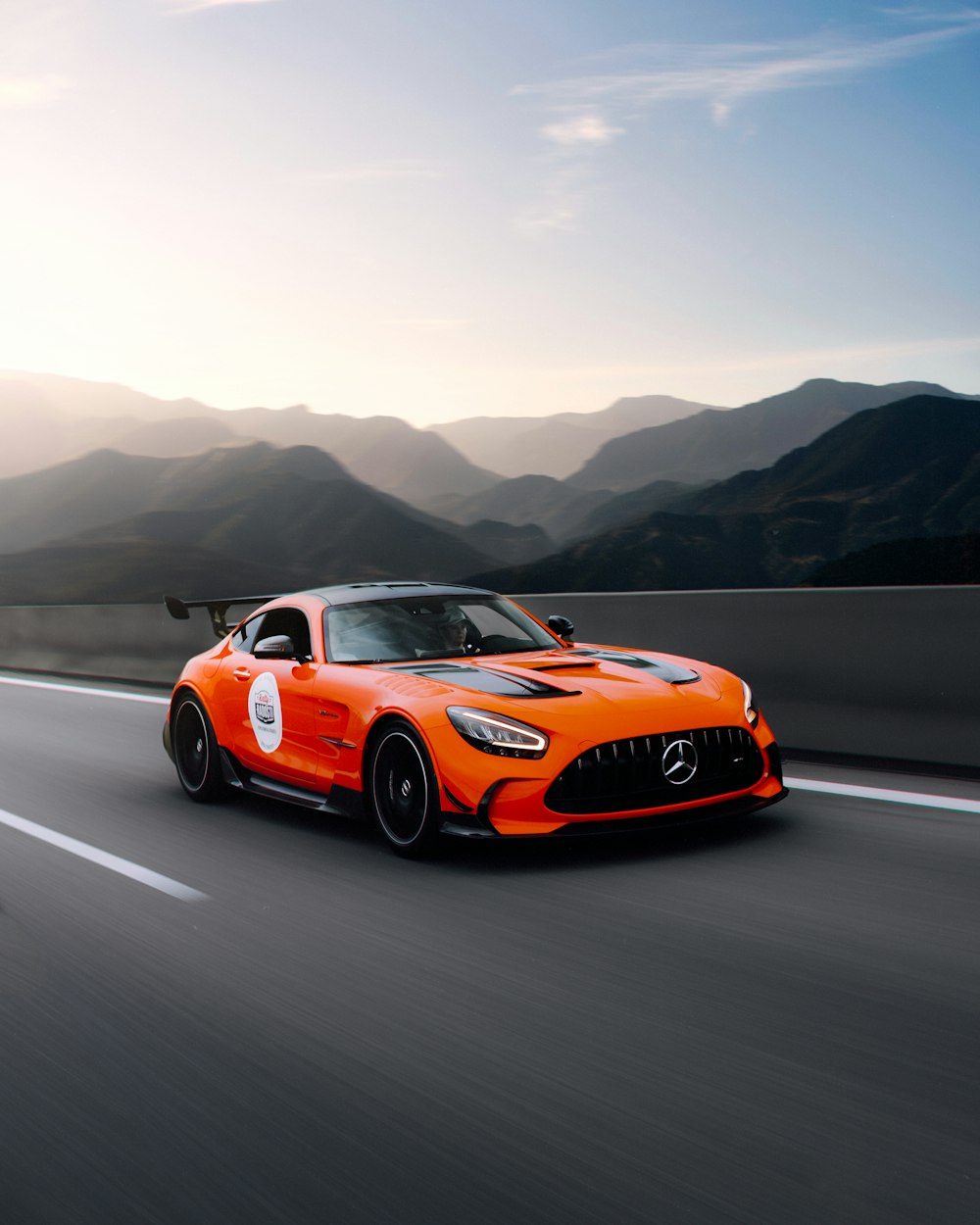 an orange sports car driving down the road
