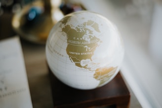 a white and gold globe sitting on top of a wooden stand
