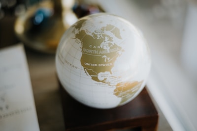 a white and gold globe sitting on top of a wooden stand