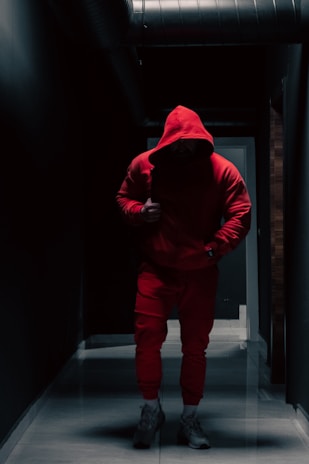 a man in a red hoodie is walking down a hallway
