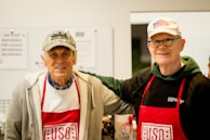 two men in red aprons standing next to each other