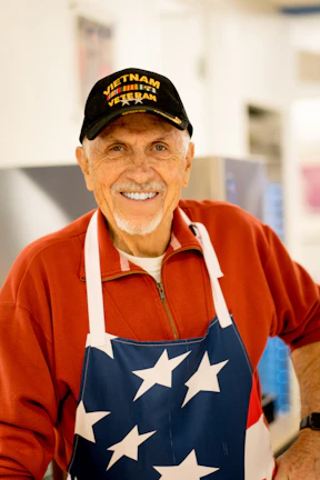 A smiling veteran receiving a hygiene kit in a warm community center.