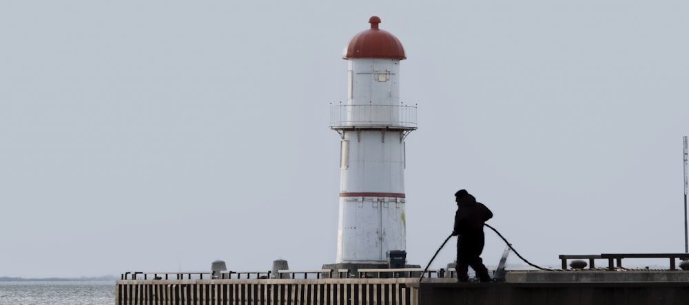 a person is standing on a pier near a light house