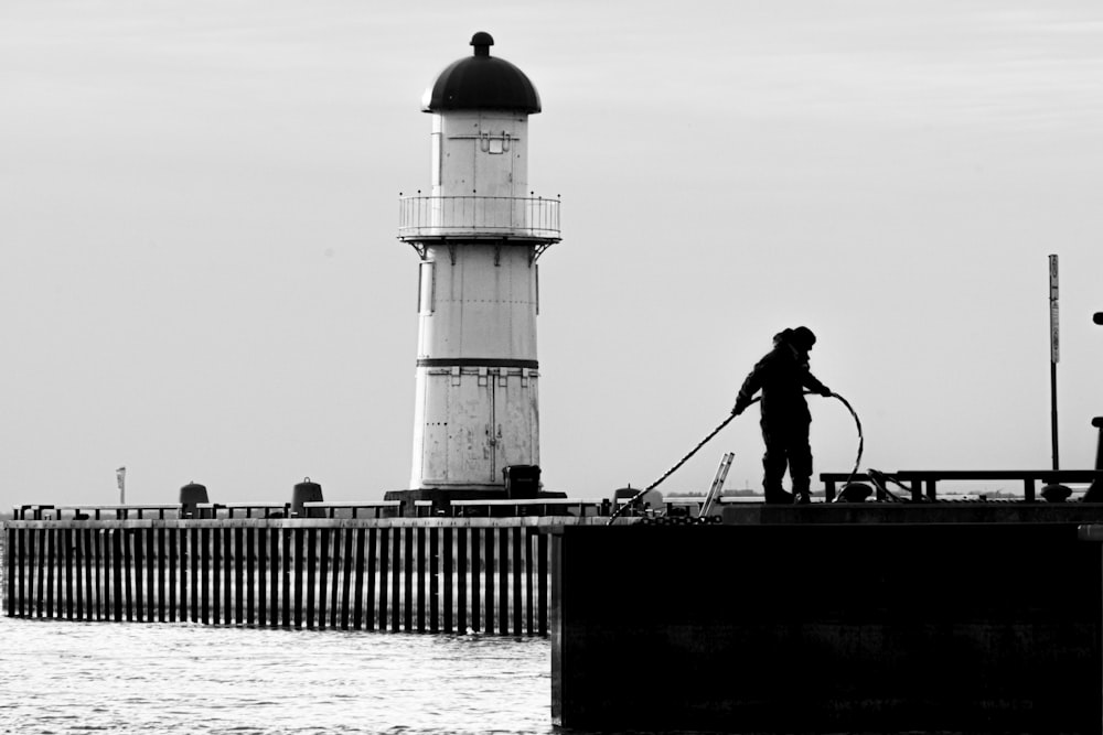 a person standing on a pier near a light house