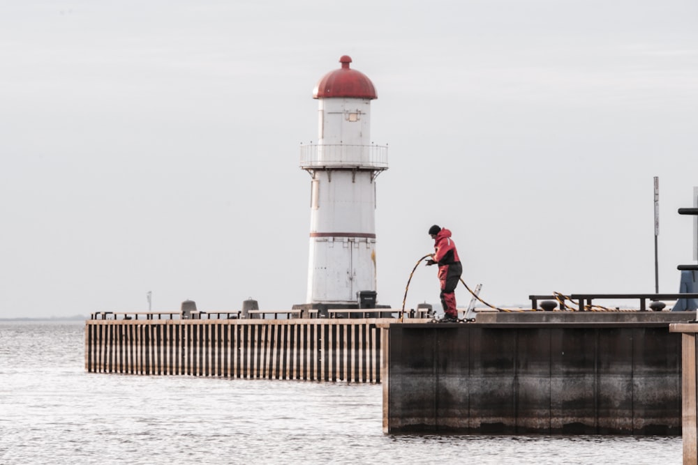 a man standing on top of a pier next to a light house