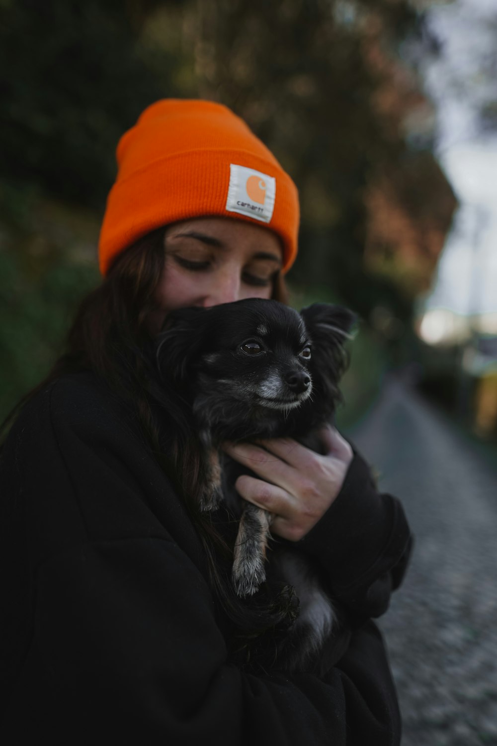 a woman in an orange hat holding a small dog
