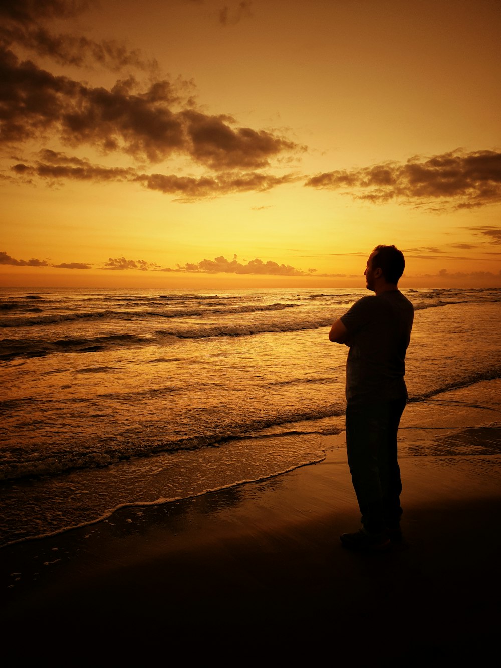 Un hombre parado en una playa al atardecer