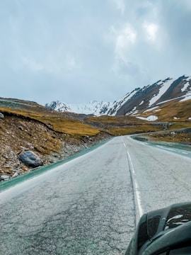 Mountain road winding through the Pyrenees with snow-covered peaks in the background.
