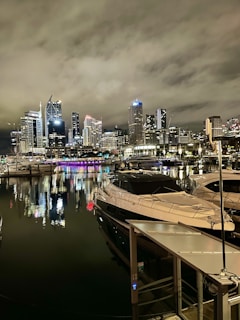 Night view of a lit-up Dubai marina with yachts docked.