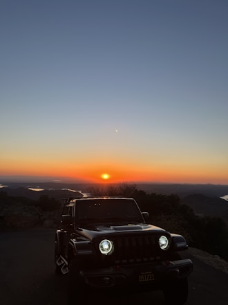 A sleek armored Land Cruiser 300 parked on a rugged terrain at sunset.