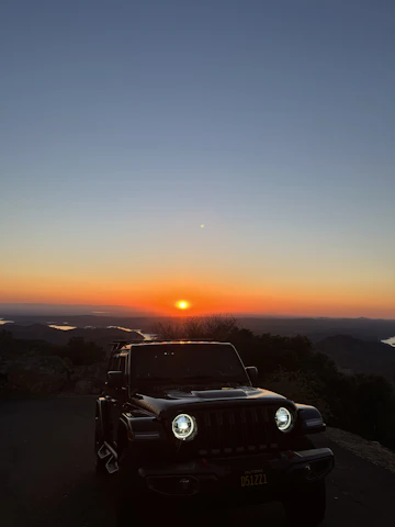 A gleaming Mahindra Thar 4x4 parked against the scenic hills of Chandigarh at sunset.
