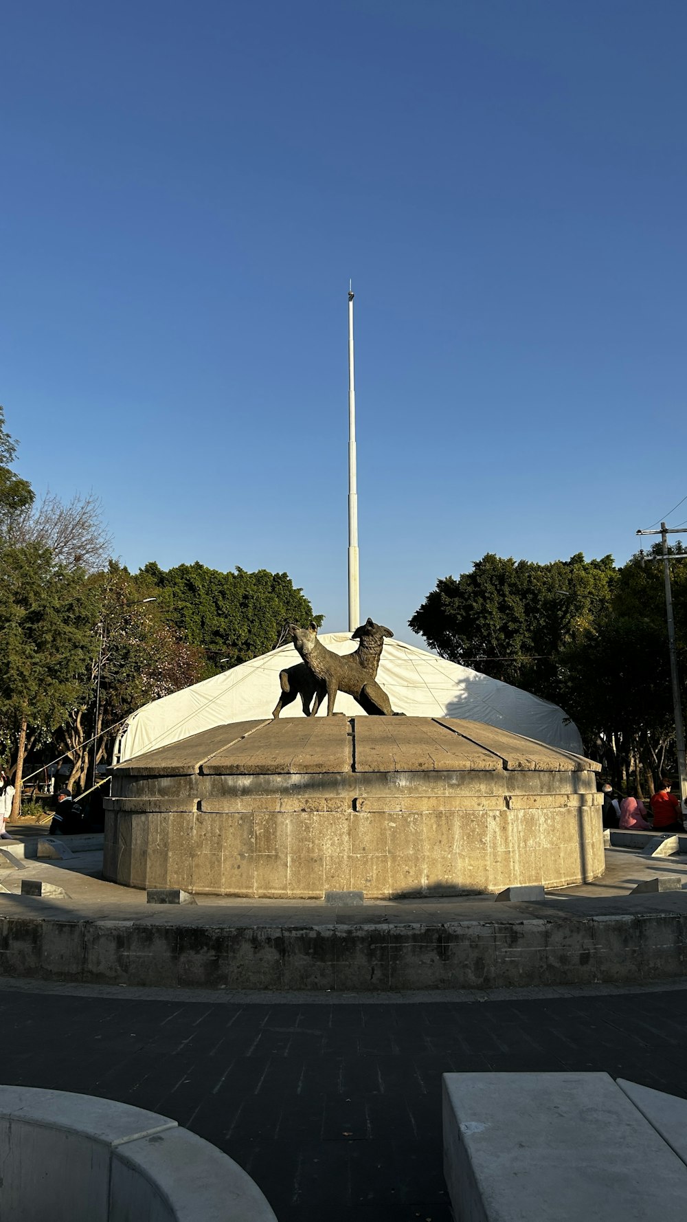 a statue of two dogs in front of a flag pole