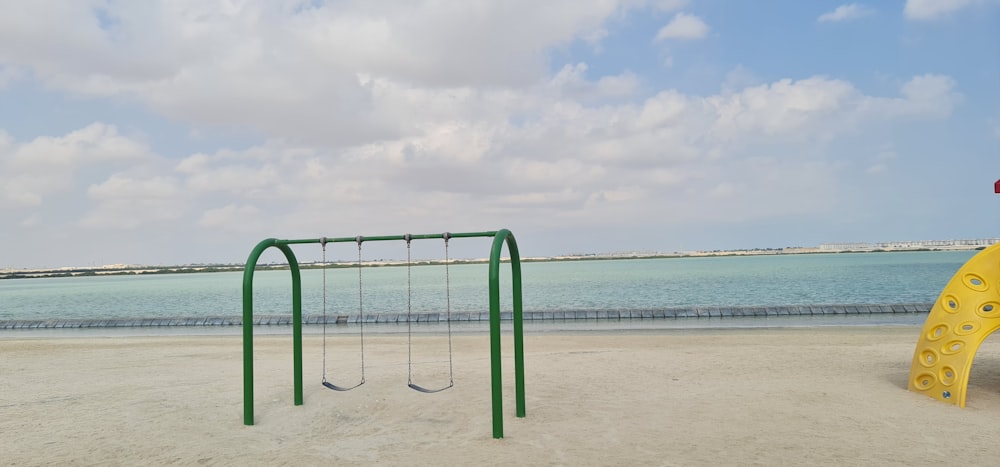 a green and yellow play set on a beach