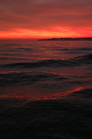 A vibrant sunset over the Pacific Ocean with radio waves symbolizing broadcast signals.