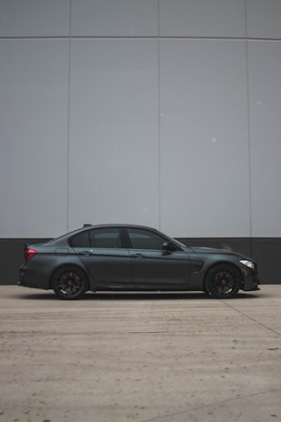 A sleek black sedan parked curbside outside San Diego International Airport, ready to welcome a passenger.