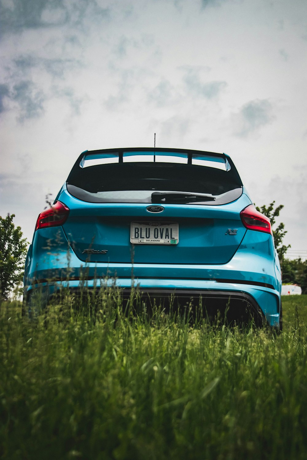 a blue car parked in a grassy field