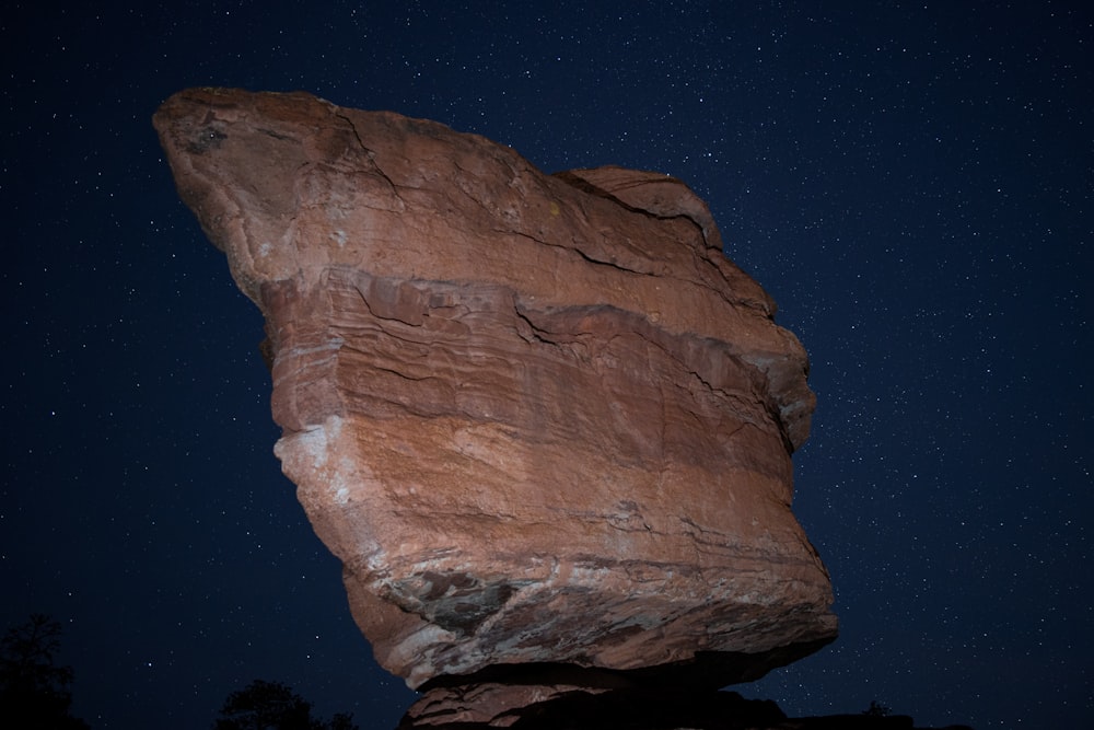a large rock with a star filled sky in the background