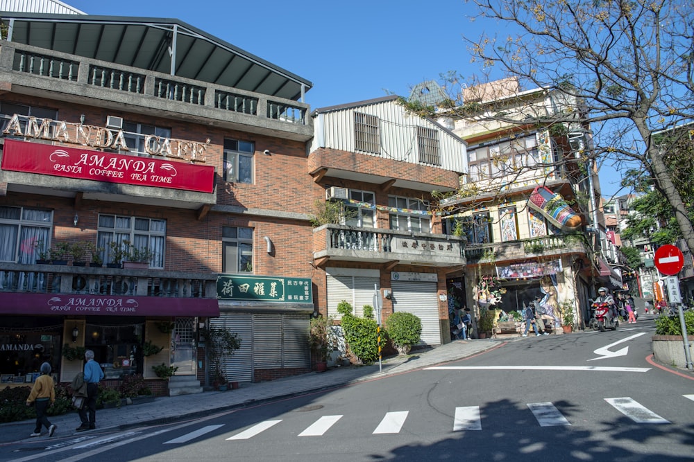 a city street with shops and people walking on the sidewalk