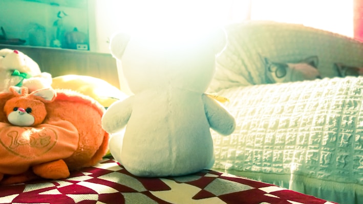 A cozy child's bedroom featuring a well-loved teddy bear resting on a soft blanket.