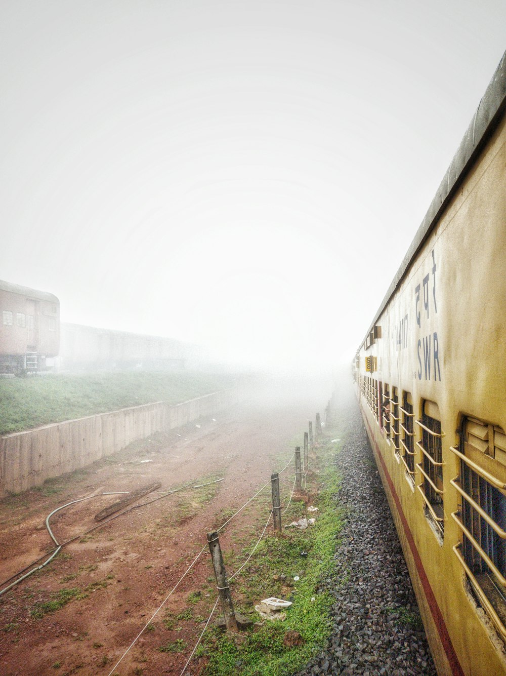 a yellow train traveling down train tracks next to a field