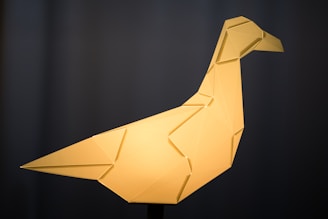a yellow origami bird sitting on top of a table